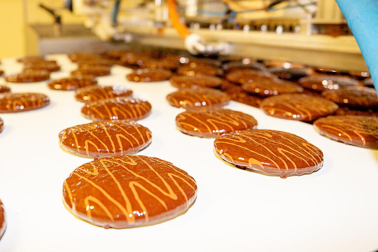 Oben Nachschub im Sekundentakt: Über ein Förderband kommen die frischen Lebkuchen zur Verpackungsanlage. Oben Nachschub im Sekundentakt: Über ein Förderband kommen die frischen Lebkuchen zur Verpackungsanlage.