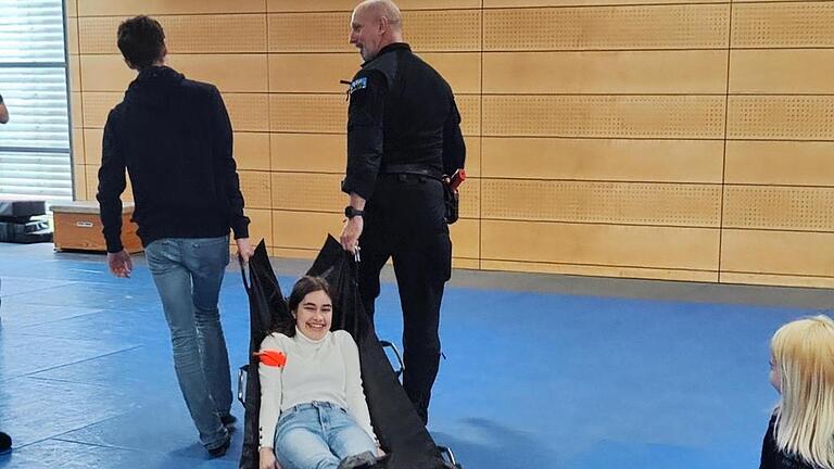 Alternative Transportmöglichkeit: Auch der Einsatz des Rettungstuchs wurde beim Besuch des P-Seminars bei der Bereitschaftspolizei Würzburg geübt. Alternative Transportmöglichkeit: Auch der Einsatz des Rettungstuchs wurde beim Besuch des P-Seminars bei der Bereitschaftspolizei Würzburg geübt.